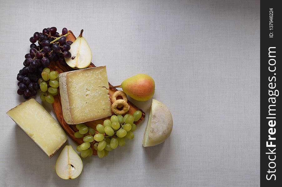 Italian cheese with pears and grapes on wooden cutboard, white background, place for text