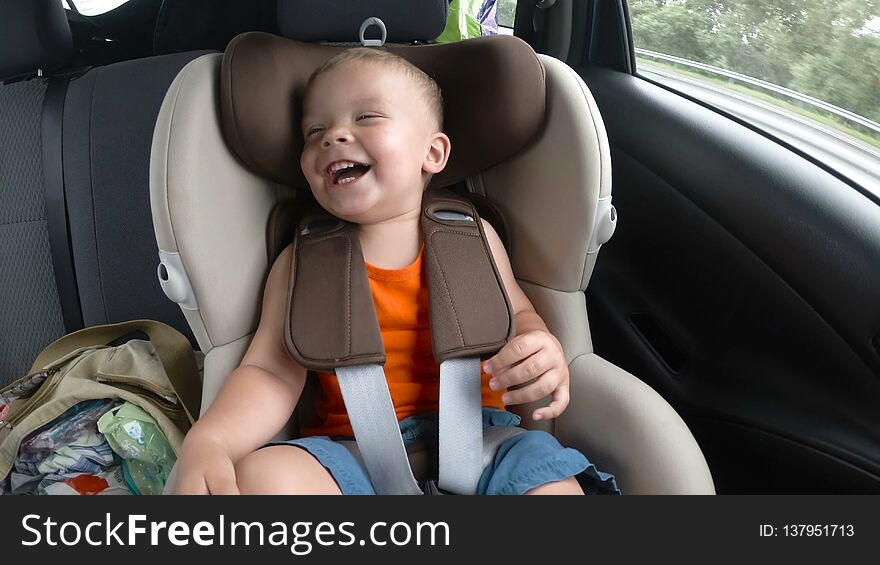 Baby Boy In The Children`s Car Seat In The Car. Kid Smiles, Laughs And Waves His Hands Happily.