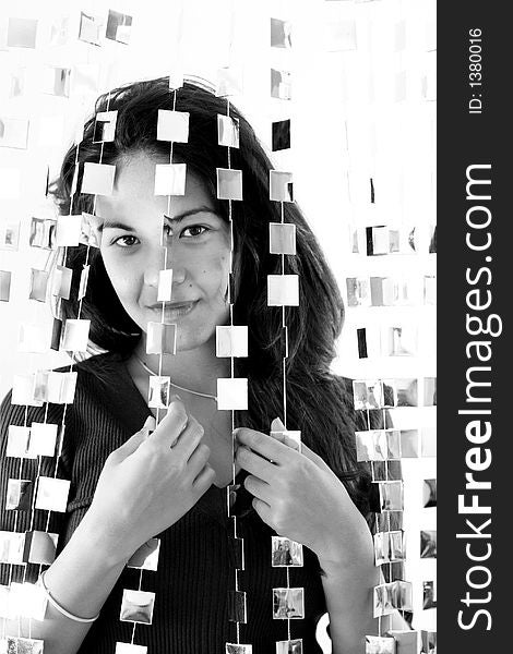 Beautiful young woman hiding behind mirrored hanging beads. Beautiful young woman hiding behind mirrored hanging beads