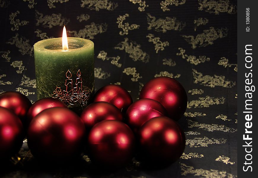 Detail green christmas candle on blue decorated background  and red balls