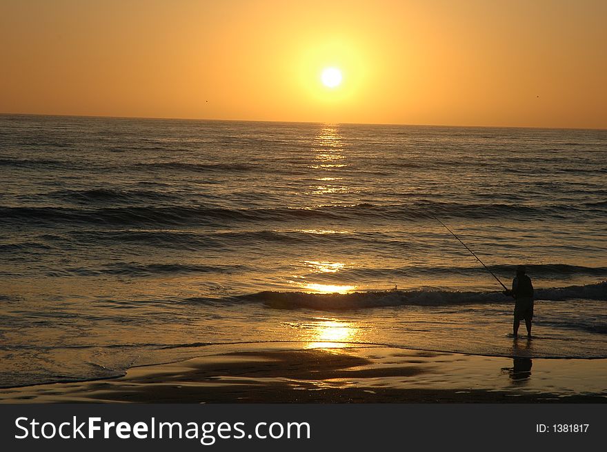 A man is fishing on the Torrey Pines beach in the beautiful San Diego just before sunset. A man is fishing on the Torrey Pines beach in the beautiful San Diego just before sunset.