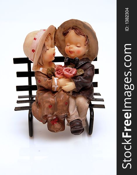 Figurine of boy and girl sitting on a bench. Figurine of boy and girl sitting on a bench