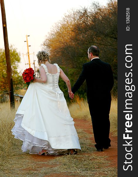 Bride and groom walking together, holding hands. Bride and groom walking together, holding hands