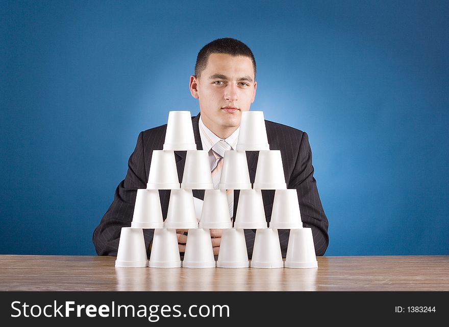 Businessman building cups' pyramid