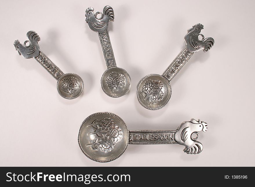 Set of unique silver measuring spoons with sunflower pattern and rooster on the handle. Set of unique silver measuring spoons with sunflower pattern and rooster on the handle