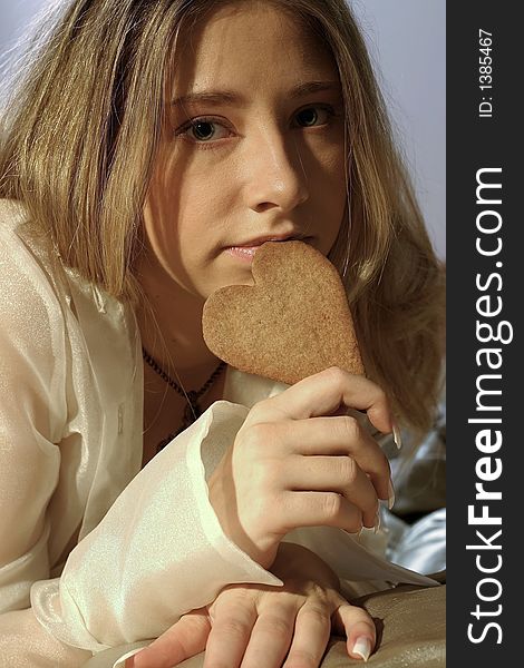 Blond girl, young woman with a ginger bread heart. Blond girl, young woman with a ginger bread heart