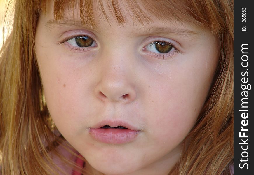 Close up of a little girl with a somewhat serious look on her face.