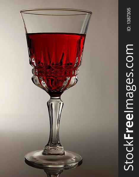 A glass of red wine highlighted from the back