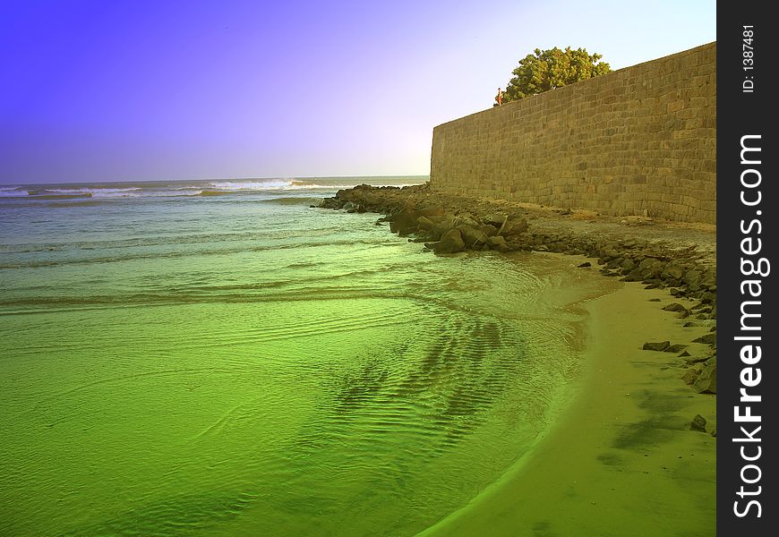 Colorful sea, nearing old and big wall.