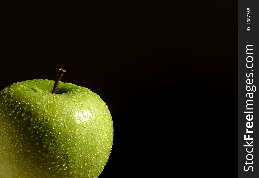 Fresh green apple splashed with water drops