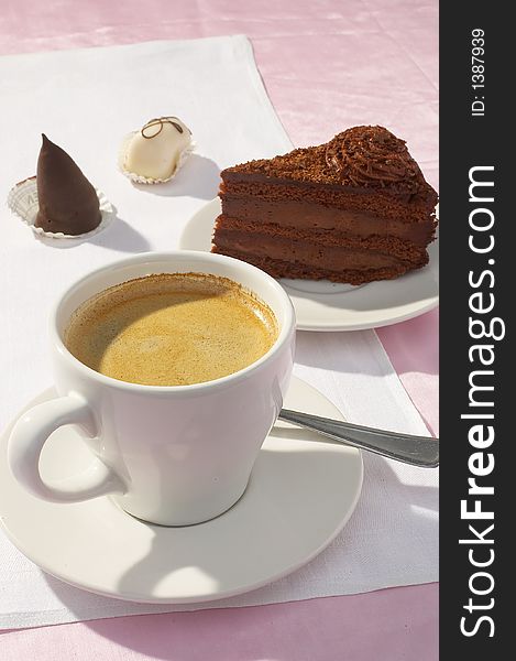 A cup of coffee and a piece of chocolate cake on white background. A cup of coffee and a piece of chocolate cake on white background