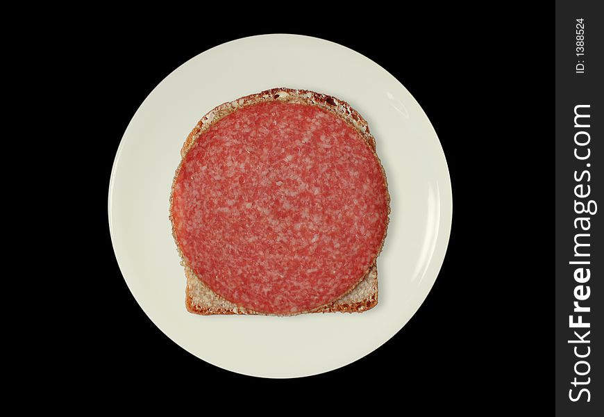 A slice of bread with salami on a white plate, isolated on black. A slice of bread with salami on a white plate, isolated on black.