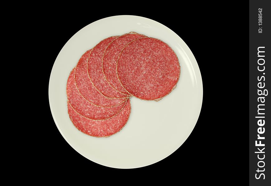 Six slices of salami on a white plate, isolated on black. Six slices of salami on a white plate, isolated on black.