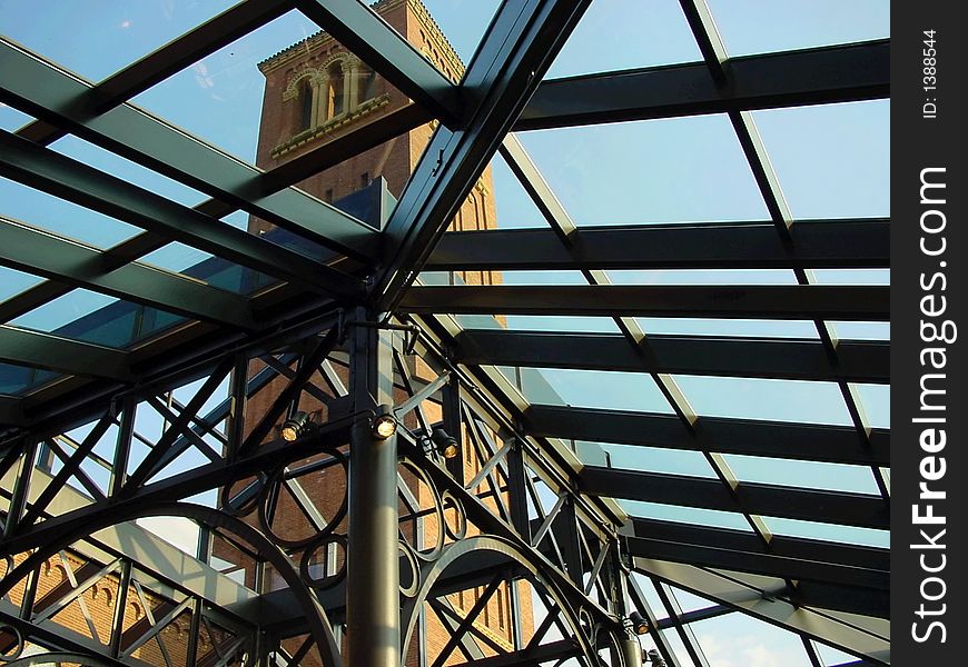 St Johns cathedral tower from the inside of a glass atrium, with metal trusses and wrought iron details