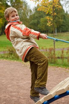 Boy In Jacket Is On Playground In Autumn Park Royalty Free Stock Image