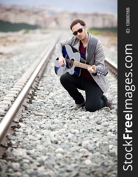 Young handsome musician playing his blue guitar.