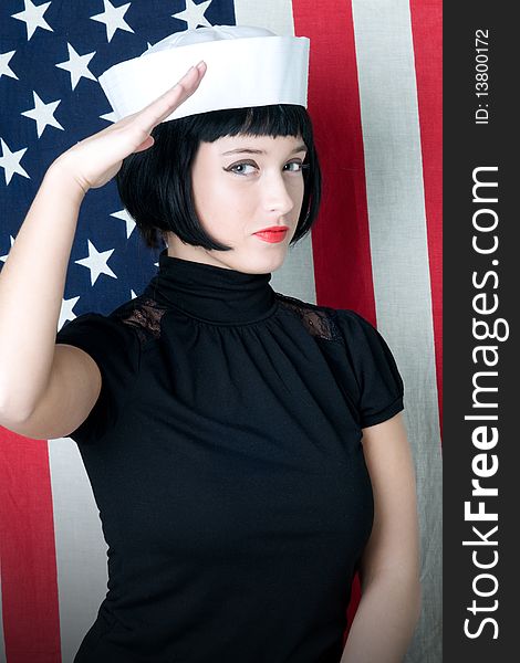Young woman saluting in sailor cap with american flag. Young woman saluting in sailor cap with american flag