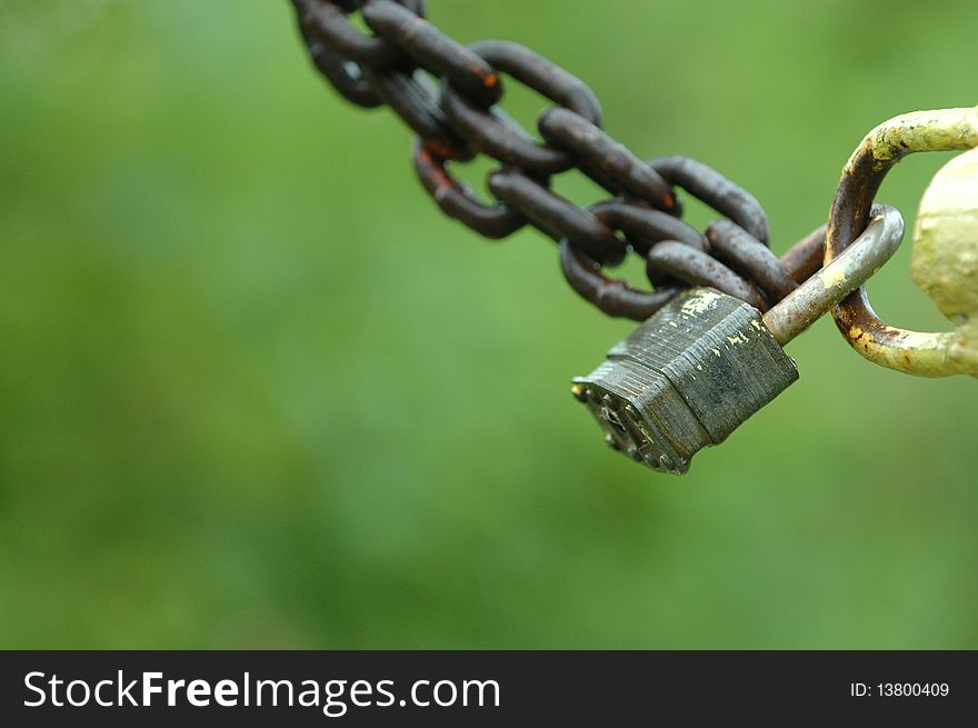 An abstract image of a large padlock and change against a natural green background. An abstract image of a large padlock and change against a natural green background.