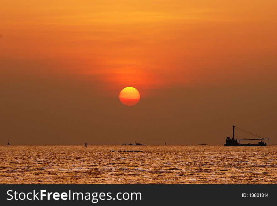 Image shows the sun setting over the sea. Sea ship and full sun on sunset time Thailand. Image shows the sun setting over the sea. Sea ship and full sun on sunset time Thailand