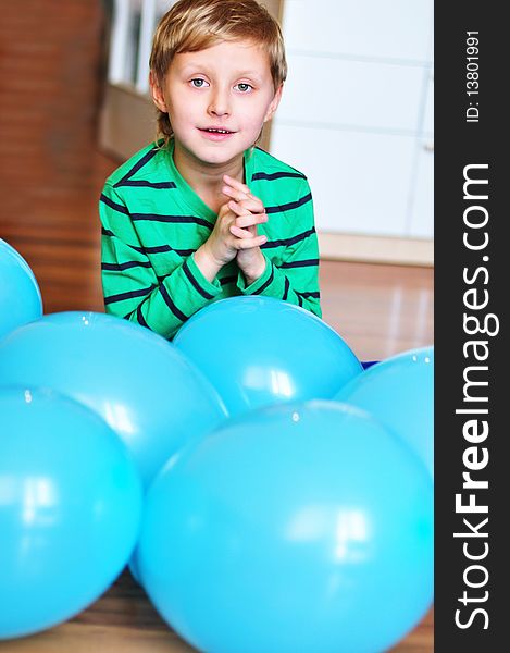 Happy boy sitting with blue  balloons on the wooden floor. Happy boy sitting with blue  balloons on the wooden floor