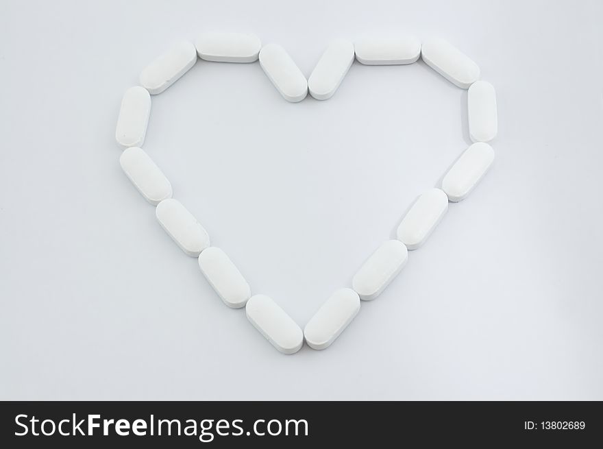 White pills in heart shape isolated on white background. White pills in heart shape isolated on white background.