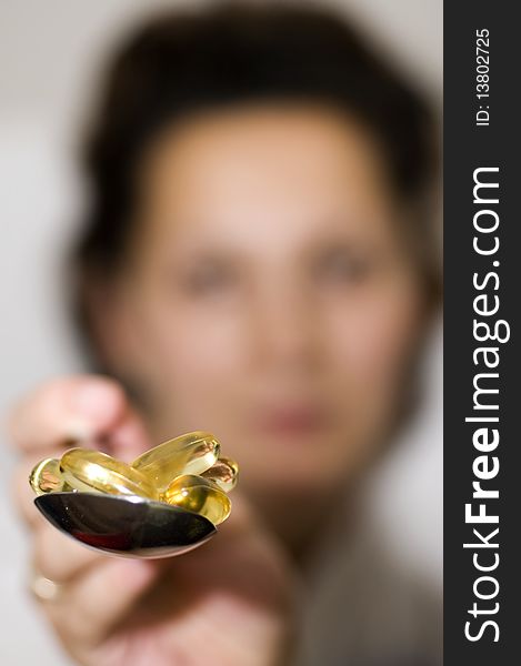 A woman holding spoon of vitamin supplements.
(focus is on the pills). A woman holding spoon of vitamin supplements.
(focus is on the pills)