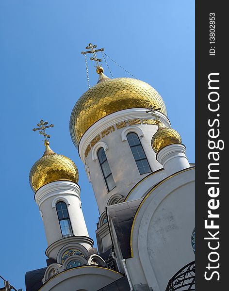 Gold domes of Orthodox Church with crosses in spring. White Romanesque building with frescos. Odessa