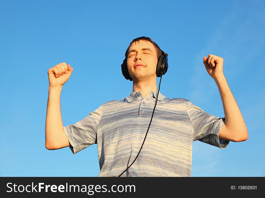 One handsome man is listening music outdoors with closed eyes.