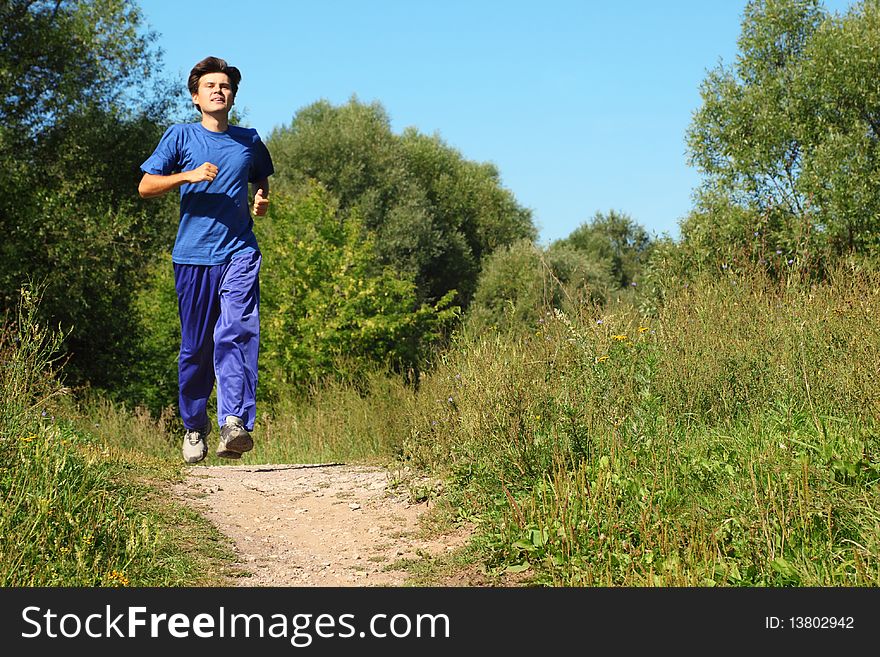 Man wearing sporty clothes is running along path