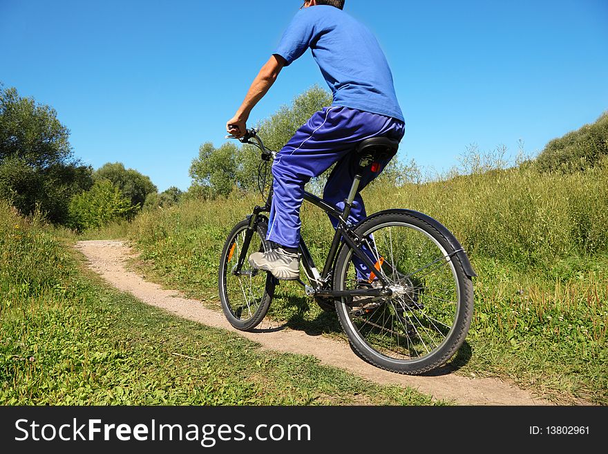 Back of man wearing sporty clothers. one man is riding on bicycle