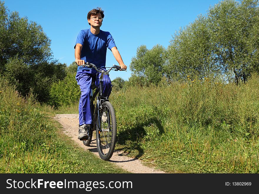One man wearing sporty clothes is riding on a bycicle and looking at camera. sunny summer day. One man wearing sporty clothes is riding on a bycicle and looking at camera. sunny summer day.