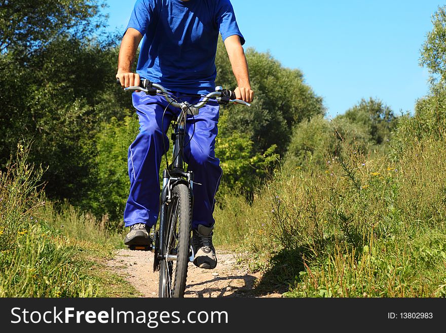 One man wearing sporty clothes is riding on a bycicle. body of man. sunny summer day.