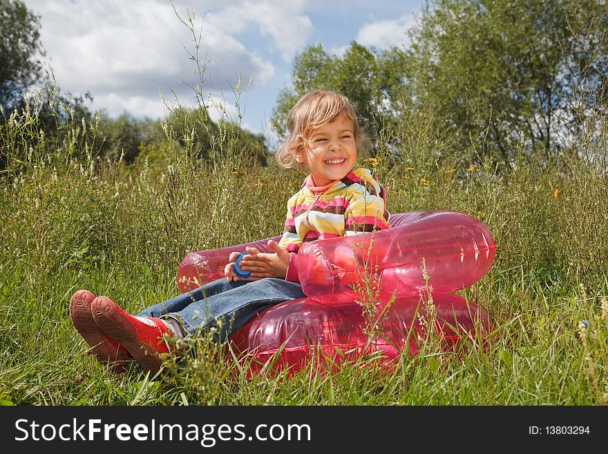 Young girl in summer day rest in the open air sitting on an inflatable armchair. Young girl in summer day rest in the open air sitting on an inflatable armchair