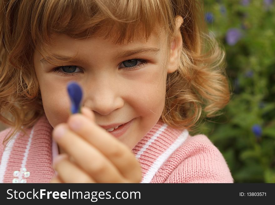 Young girl holding in her hand annual delphinium, around flowers area