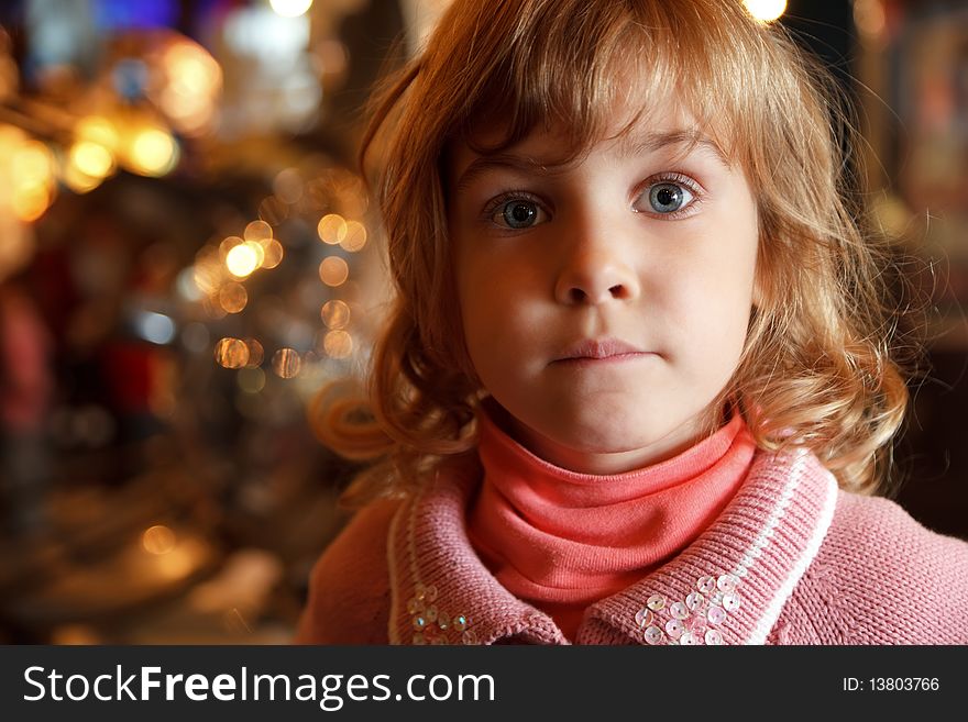 Portrait of charming little girl in background lights. Close-up. Indoors. Portrait of charming little girl in background lights. Close-up. Indoors.