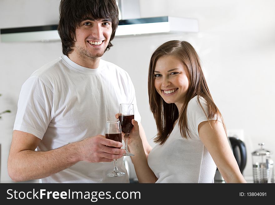 Beautiful girl and boy with wineglasses on kitchen