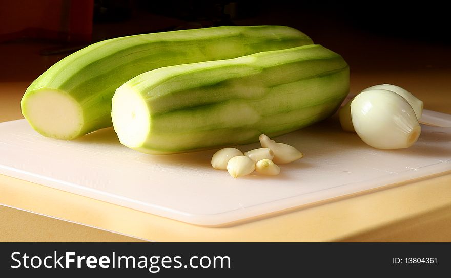 Peeled zucchini with onion and garlic on cutting board