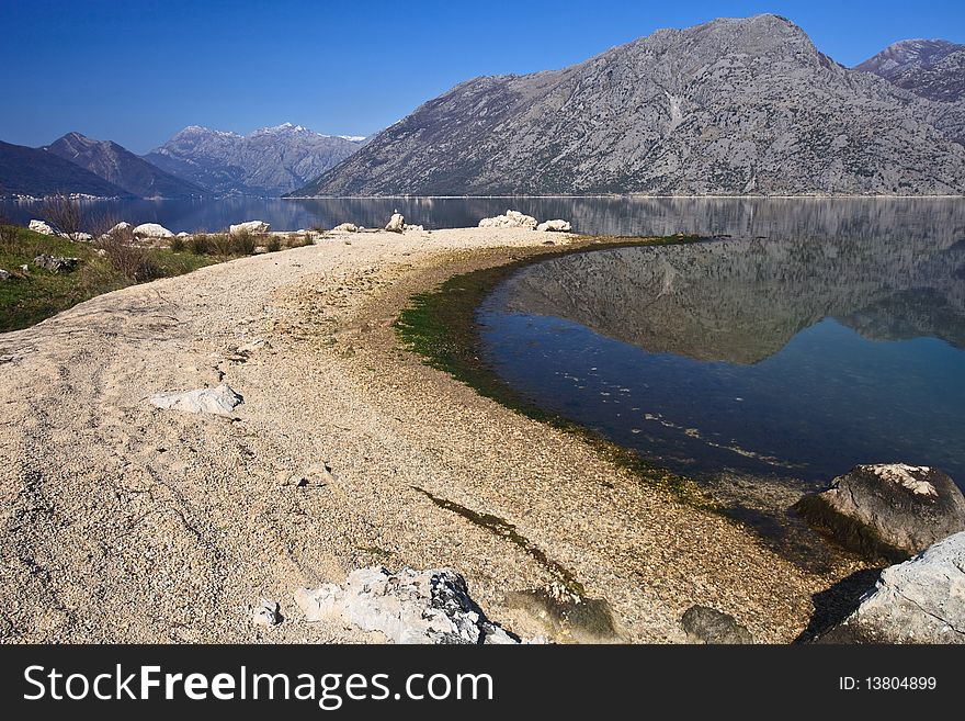 A curved pebble beach beside a calm lake