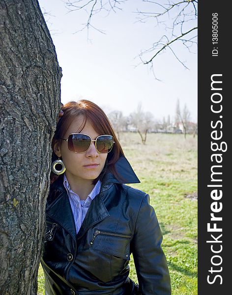 Beatiful girl staying near the tree trunk