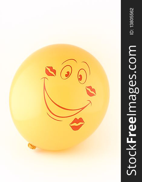 Smiling yellow balloon in the imprints kisses filmed in close-up on a white background without isolation