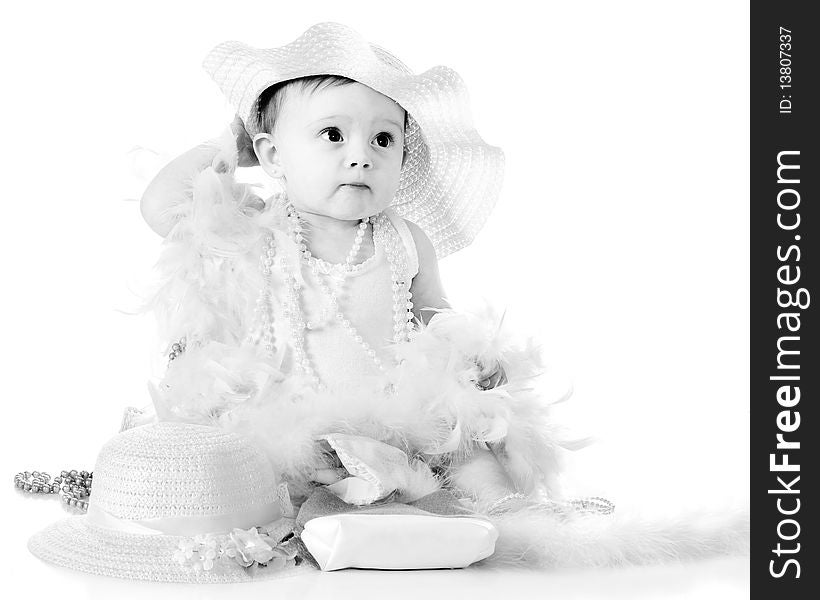 A beautiful baby girl gussied up with a fancy hat, beads and boas. High key black and white. A beautiful baby girl gussied up with a fancy hat, beads and boas. High key black and white.