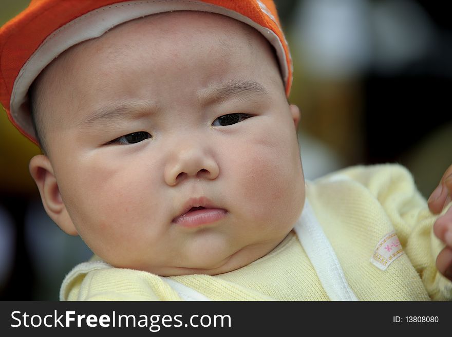 A cute baby with a orange cap.