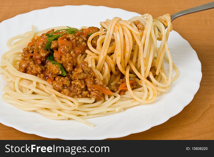 A fork lifting spaghetti above a plate
