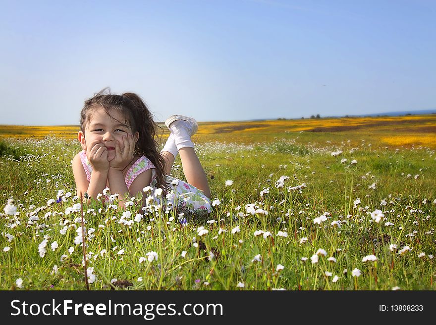 Little girl sitting in a field of white flowers