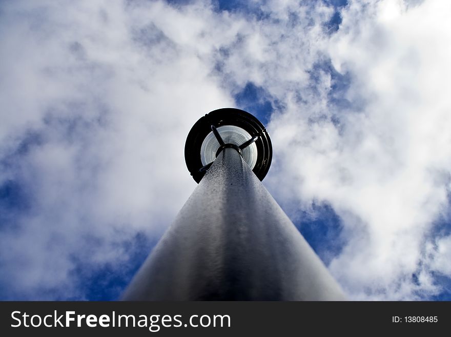 A photograph of a light pole from an uncommon perspective, looking straight up the pole.  There is a saturated blue sky background with bellowing white clouds.  The photograph was taken on a brisk clear winter day. A photograph of a light pole from an uncommon perspective, looking straight up the pole.  There is a saturated blue sky background with bellowing white clouds.  The photograph was taken on a brisk clear winter day.