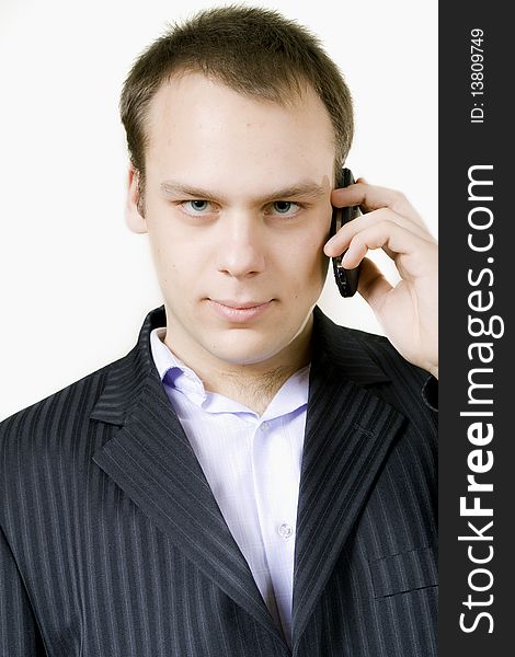Young businessman, talking over a cellphone, looking at the camera. Young businessman, talking over a cellphone, looking at the camera