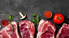 Meat Raw Steaks Lie On Black Background With Vegetables, Tomatoes, Marasmade, Mushrooms. Background Image. Top View Royalty Free Stock Images Meat Raw Steaks Lie On Black Background With Vegetables, Tomatoes, Marasmade, Mushrooms. Background Image. Top View Royalty Free Stock Images