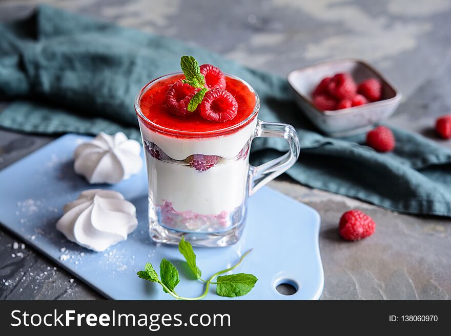 Delicious layered dessert with crushed meringue kisses, curd, raspberries and whipped cream in a glass jar