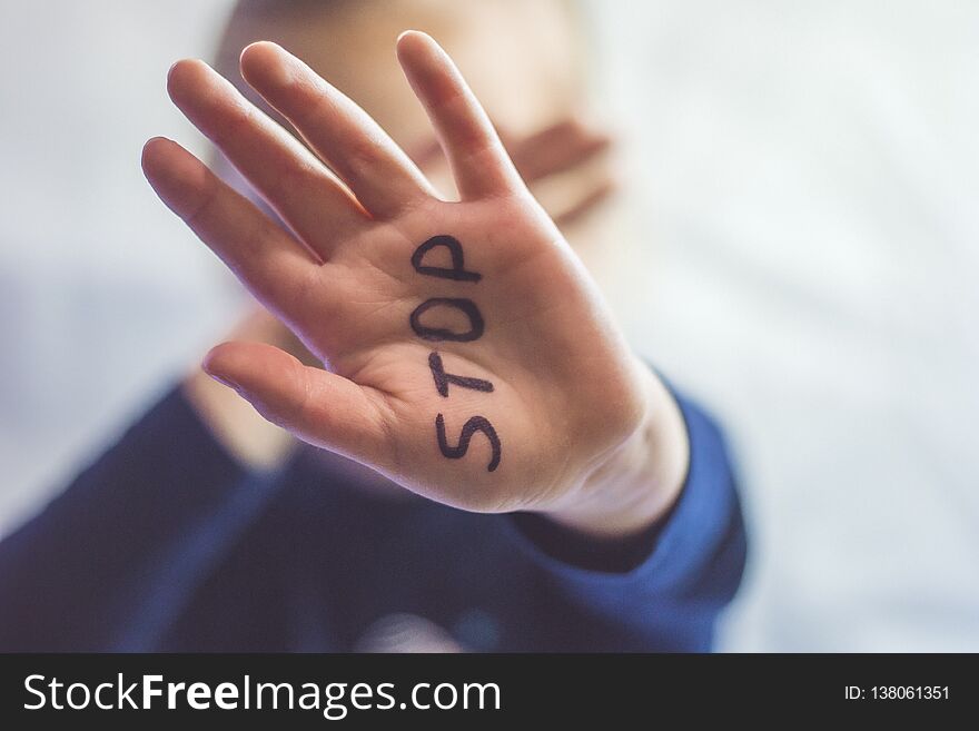 Little frightened girl shows the word Stop written on the arm. Children are subjected to violence and publishing in the home and