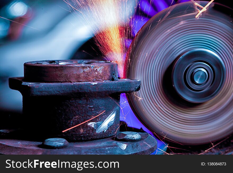 A young man welder grinder metal an angle grinder in the workshop, sparks fly to the side. A young man welder grinder metal an angle grinder in the workshop, sparks fly to the side